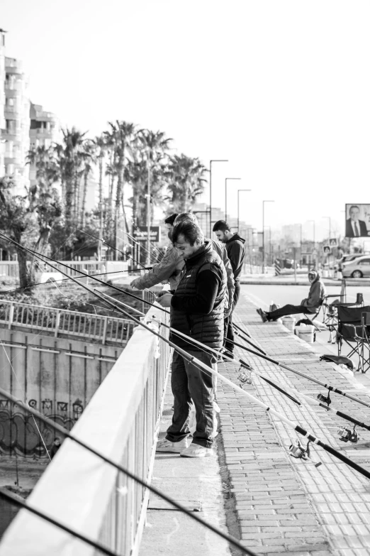 a black and white photo of two men fishing, a black and white photo, by Ismail Acar, unsplash, realism, tel aviv street, cables hanging, at the terrace, tending on art station