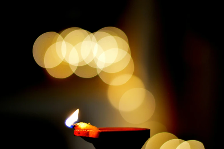 a lit candle sitting on top of a table, hindu stages of meditation, blurred, emerging from a lamp, festivals