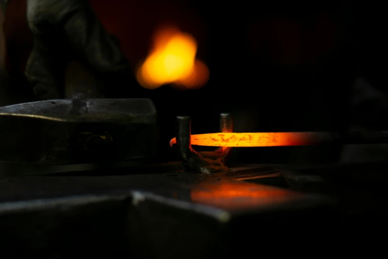 a close up of a metal object on a table, by Adam Marczyński, pexels contest winner, fire beam, working in the forge, photographed for reuters, orange glow