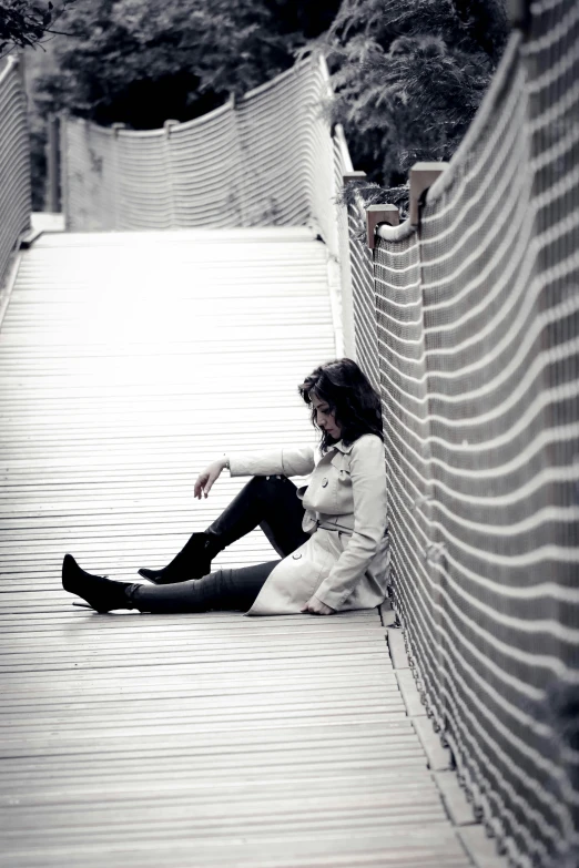 a black and white photo of a person sitting on a bridge, she is distressed, on the ground, !!! colored photography, candid photography