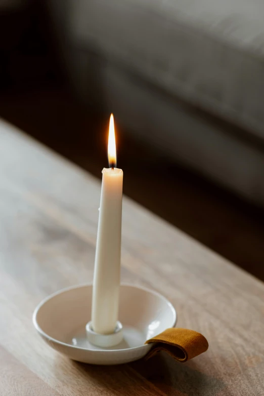 a white candle sitting on top of a wooden table, lemon, hero shot, medium angle, square