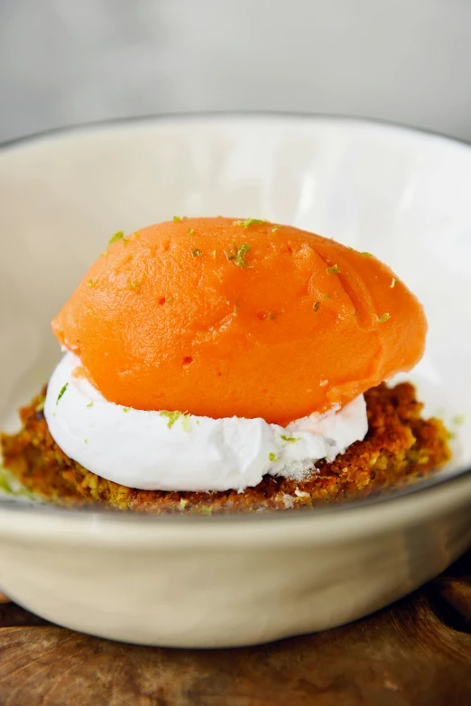 a close up of a bowl of food on a table, orange head, whipped cream on top, sponge, sharply shaped