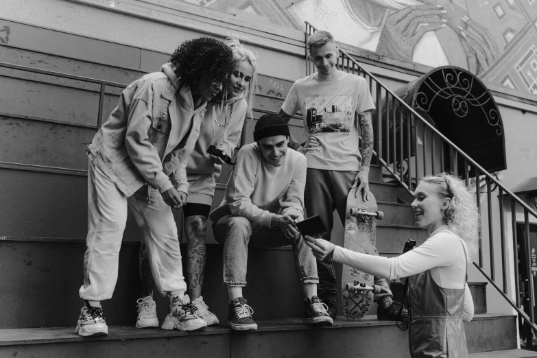 a group of people sitting on the steps of a building, a black and white photo, by Christen Dalsgaard, pexels, antipodeans, wearing dirty overalls, die antwoord style wear, skateboarder style, looking happy