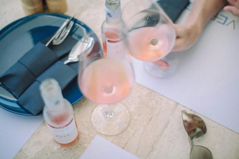 a couple of wine glasses sitting on top of a table, happening, pink concrete, holding wine bottle, zoomed in, mixing drinks