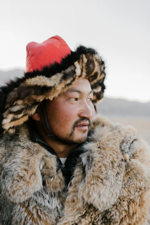 a man wearing a fur coat and a red hat, hurufiyya, cover photo portrait of du juan, in the steppe, profile image, portrait featured on unsplash