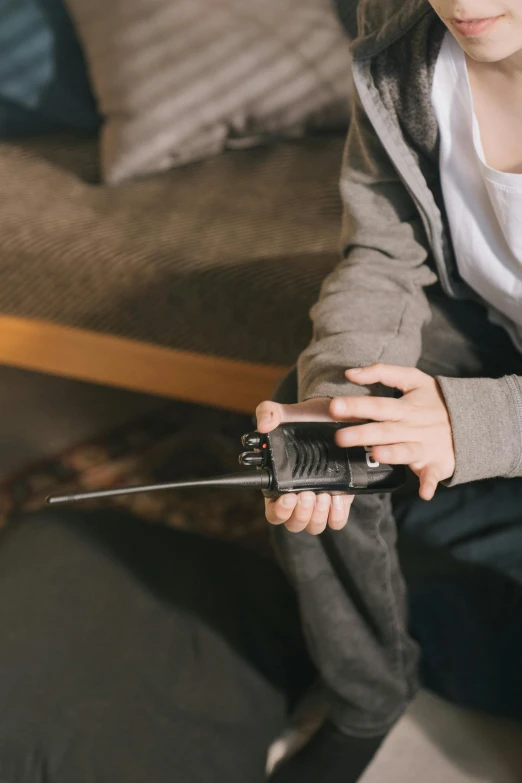 a person sitting on a couch holding a radio, pexels, of a lightsaber hilt, kid named finger, holding a wrench, high quality photo