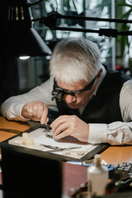a man sitting at a desk working on a piece of paper, an engraving, by László Balogh, reddit, magnifying glass, platinum jewellery, hasselblad quality, klaus schwab eating bugs