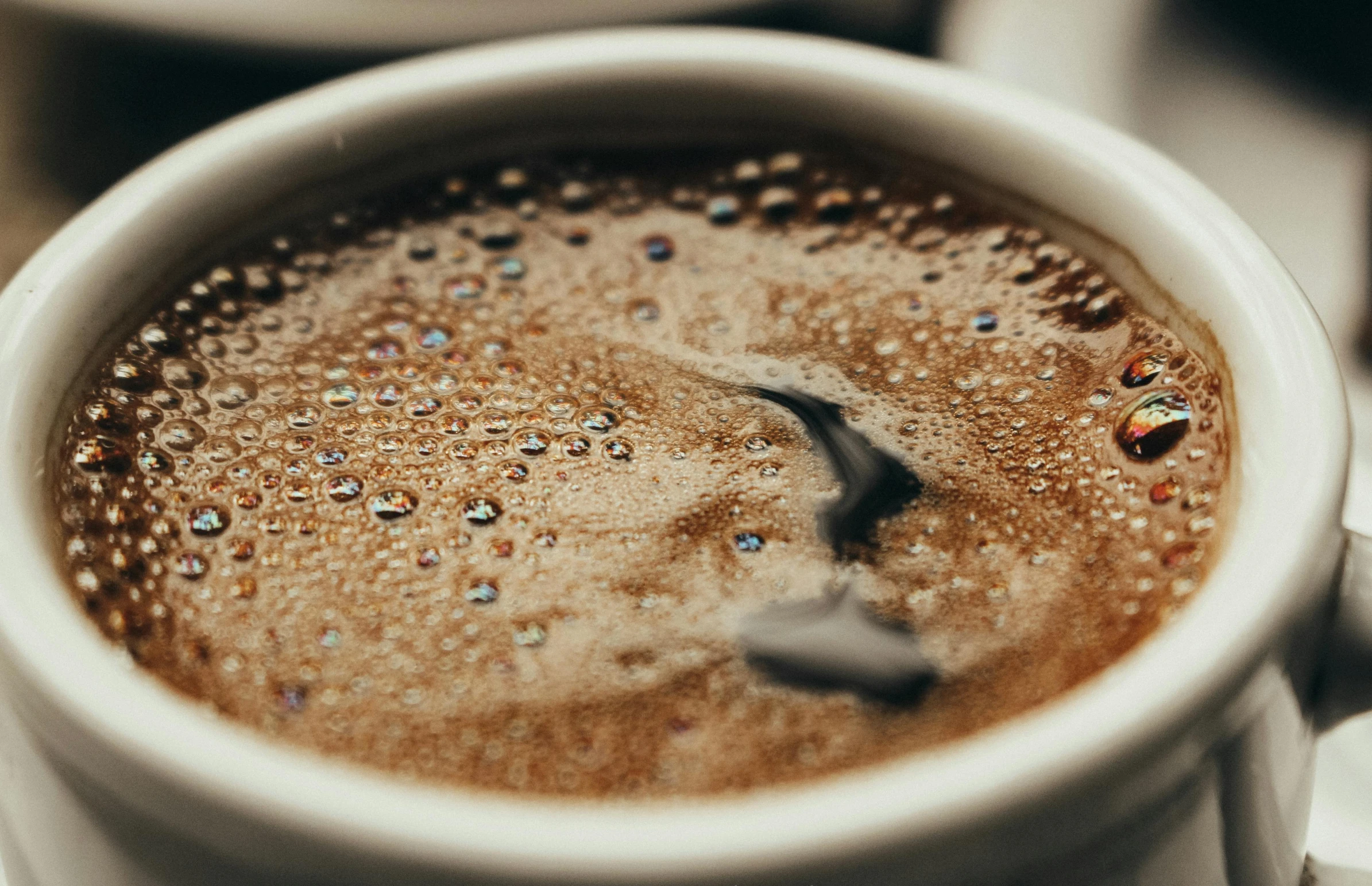 a close up of a cup of coffee on a table, a stipple, trending on pexels, brown water, sparkly, soup, thumbnail