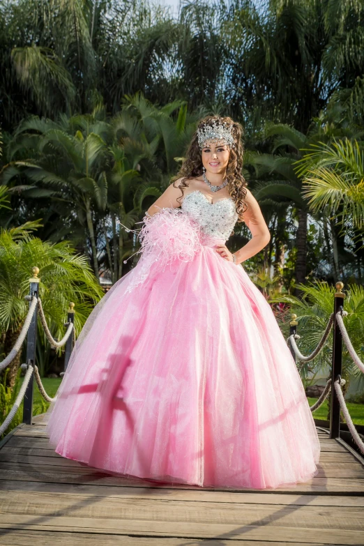 a young girl in a pink dress standing on a bridge, by Randy Gallegos, wearing a pink ballroom gown, lush surroundings, slide show, latinas