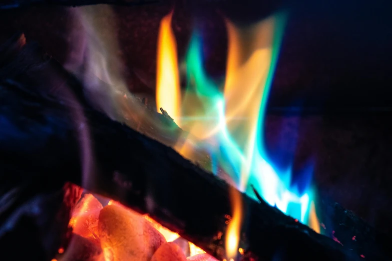 a close up of a fire with colorful flames, by Jan Rustem, pexels contest winner, cold colour temperature, with cinematic colour palette, neon glowing wood, rainbow colored