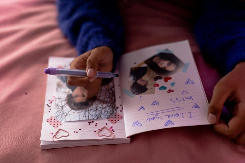 a person holding a pen and writing on a book, an album cover, taken with kodak portra, hearts, child drawing, ((portrait))