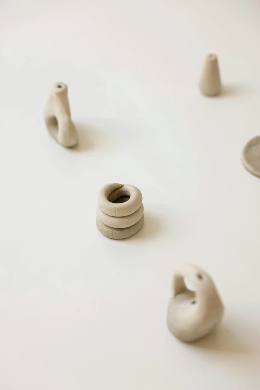 a number of small objects on a white surface, an abstract sculpture, by Rebecca Horn, unsplash, made of clay, rings, small nose, 2030s