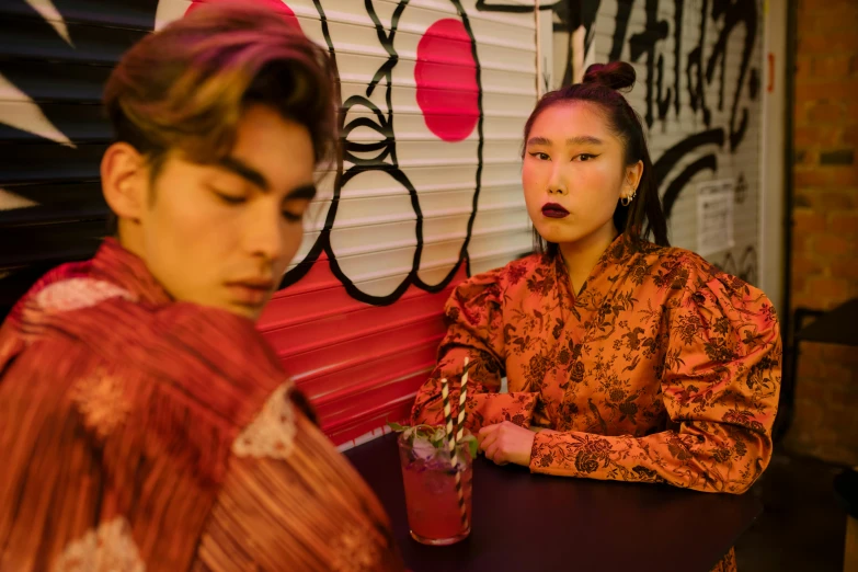 two women sitting at a table with drinks, a portrait, trending on pexels, ukiyo-e, asian man, colorful with red hues, fashion shoot 8k, looking threatening