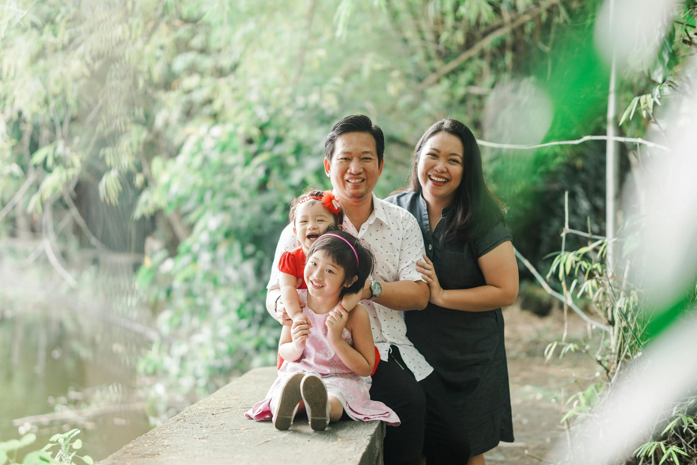 a family poses for a picture on a bridge, a portrait, pexels, happening, an indonesian family portrait, lush surroundings, avatar image