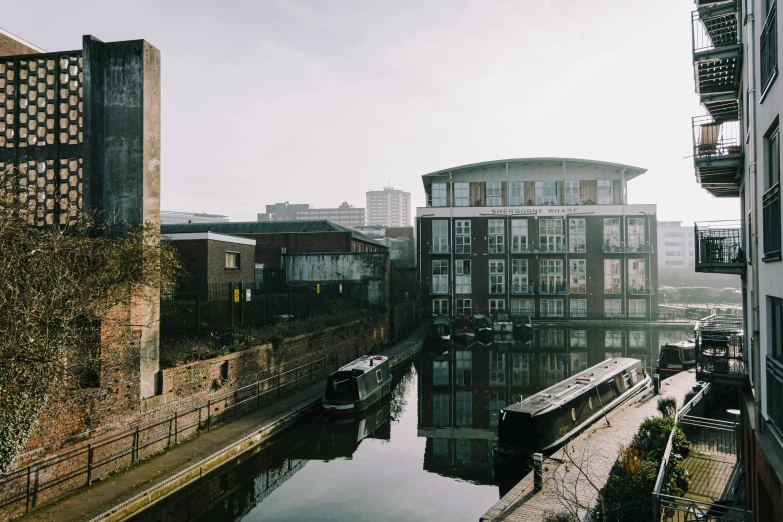 a river running through a city next to tall buildings, by Lee Loughridge, pexels contest winner, brutalism, canal, cosy, 3 boat in river, art deco factory