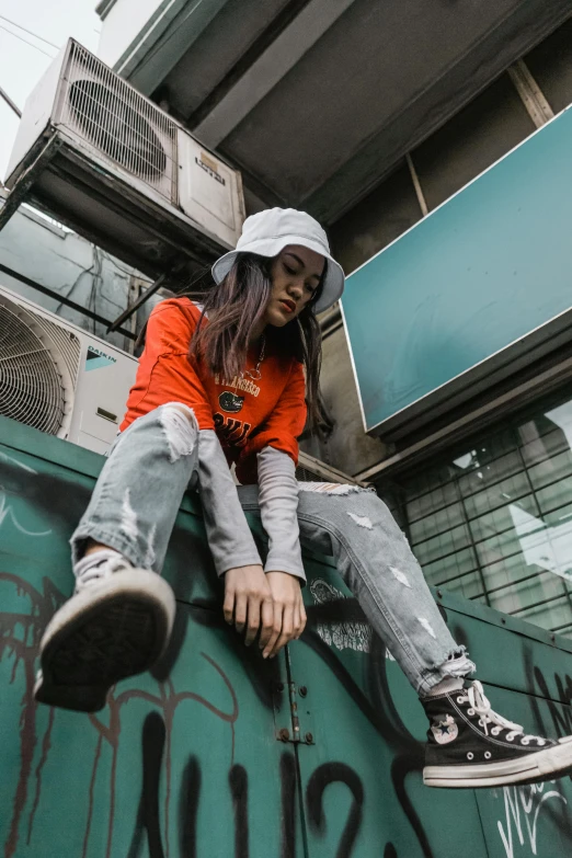 a woman sitting on top of a green box, trending on pexels, graffiti, grey orange, japanese streetwear, profile pic, vietnamese woman