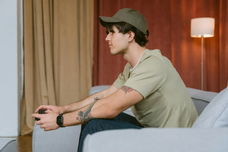 a man sitting on a couch playing a video game, by Andrew Stevovich, pexels contest winner, hyperrealism, wearing a backwards baseball cap, avatar image, 35mm color photo, adam driver