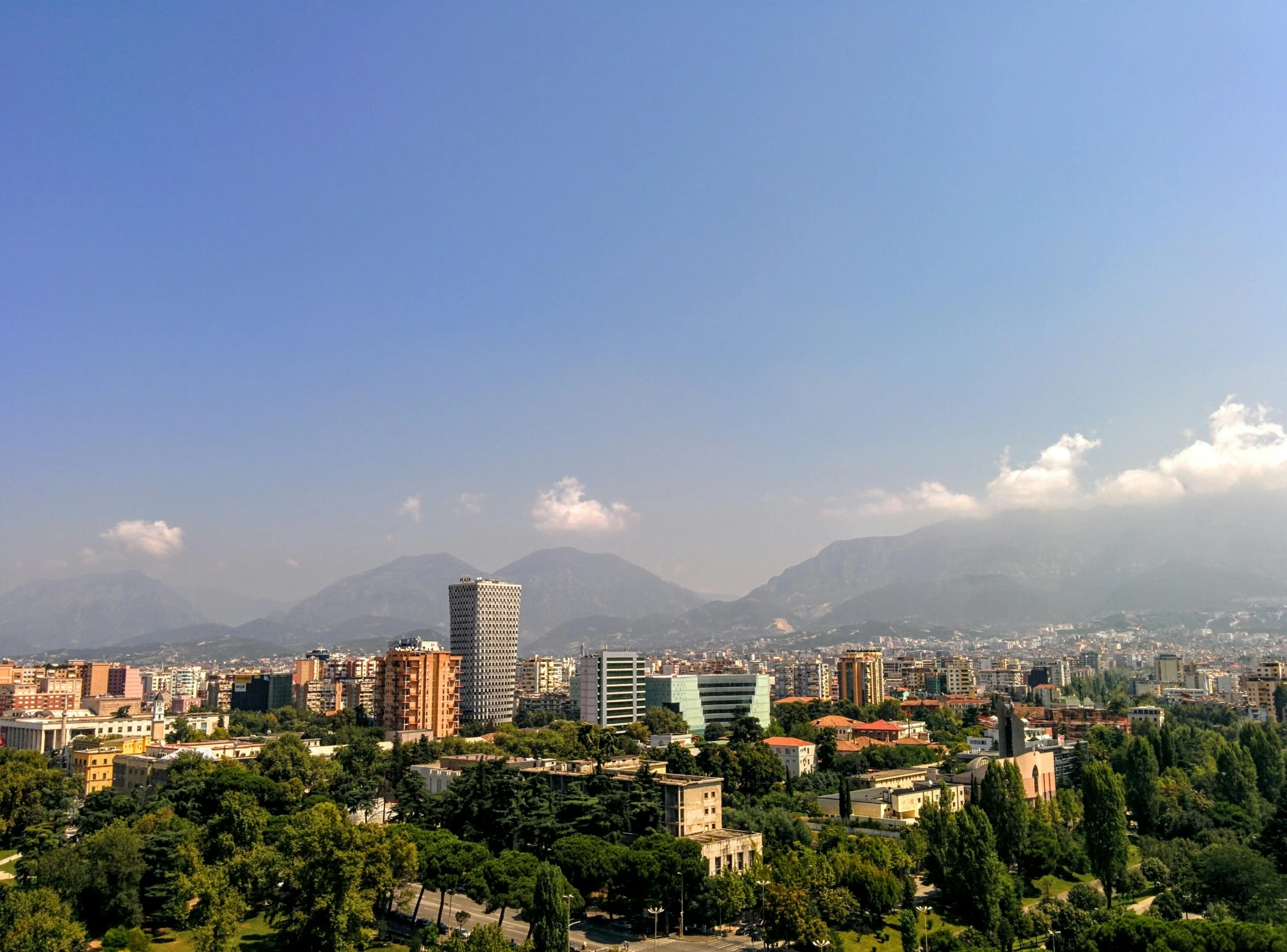 a view of a city with mountains in the background, by Alejandro Obregón, pexels contest winner, neoclassicism, bright summer day, gigapixel photo, city park, epic 3 d omolu