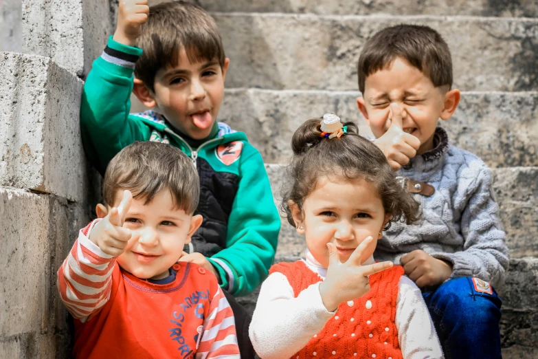 a group of children sitting next to each other, by Arthur Sarkissian, pexels contest winner, hand on his cheek, thumb up, 4yr old, thumbnail