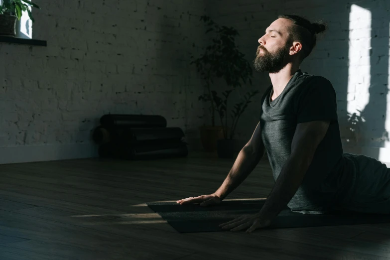 a man sitting on the floor in a yoga pose, light and space, bearded and built, profile image, thumbnail