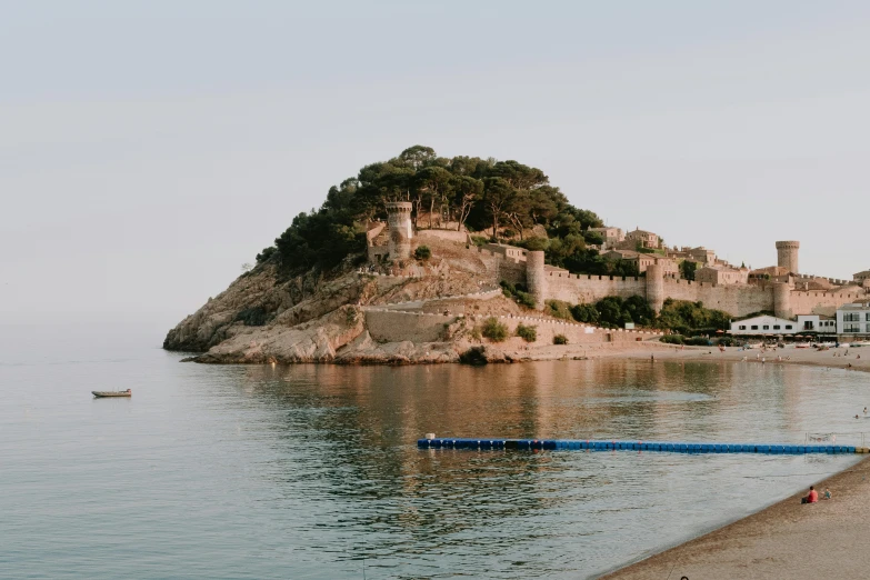 a group of people standing on top of a beach next to a body of water, castle on the mountain, mina petrovic, unsplash transparent, mediterranean fisher village
