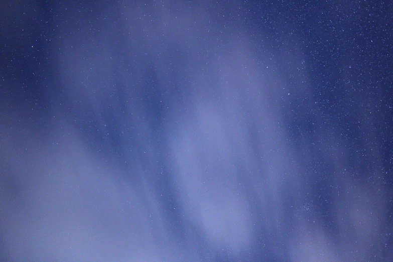 a group of people riding skis on top of a snow covered slope, the night sky, during the night, it is night time, meteors