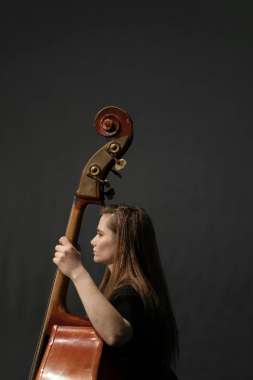 a woman playing a cello against a black background, profile picture, on a gray background, linsey levendall, museum quality photo