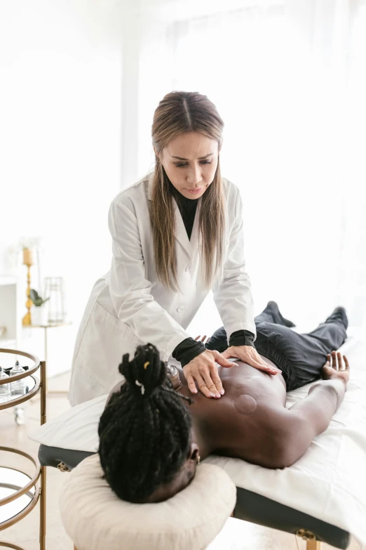 a woman getting a back massage at a spa, by Gavin Hamilton, trending on pexels, wearing lab coat and a blouse, jemal shabazz, on a white table, dissection relief