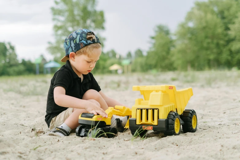 a little boy playing in the sand with a toy truck, pexels contest winner, yellow and charcoal, official product photo, chunky build, denim