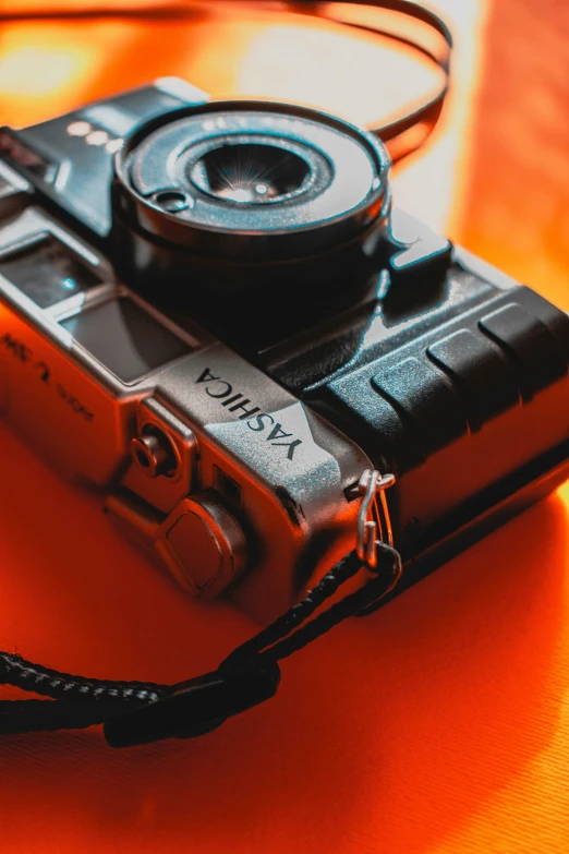 a close up of a camera on a table, vibrant orange, yashica me - 1, vibrant high contrast, today\'s featured photograph 4k