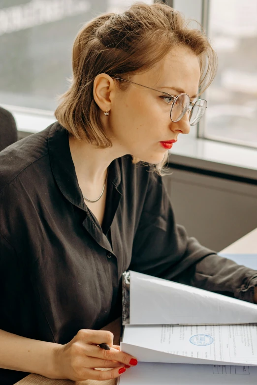 a woman sitting at a desk in front of a laptop computer, by Adam Marczyński, trending on pexels, modernism, wearing a black shirt, librarian, serious business, decorative