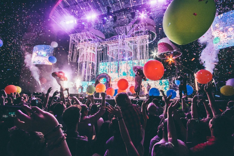 a crowd of people at a concert with balloons in the air, by Joe Bowler, maximalism, dreamworld, at a rave, globes, soaked