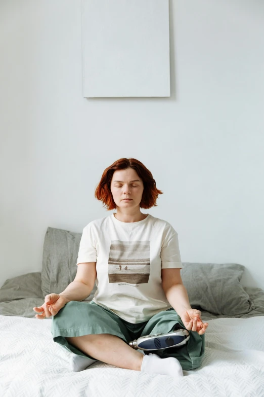 a woman sitting in a meditation position on a bed, inspired by Elsa Bleda, pexels, renaissance, a redheaded young woman, wearing a light shirt, annoyed, minimalistic