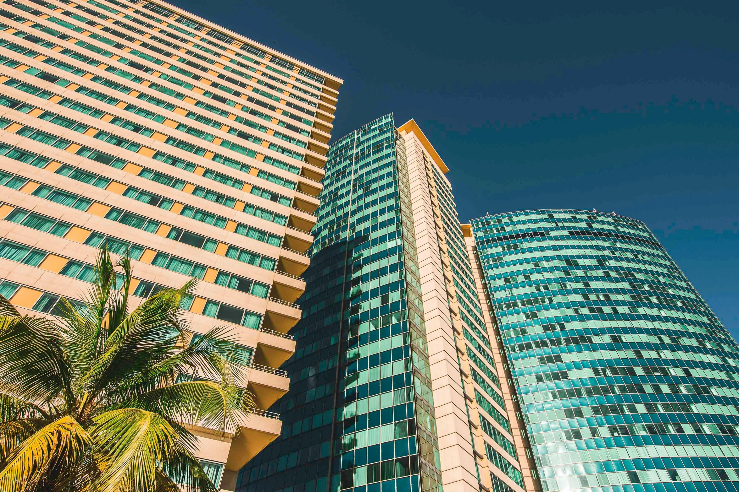 a couple of tall buildings next to a palm tree, aquamarine windows, philippines, corporate, multiple stories