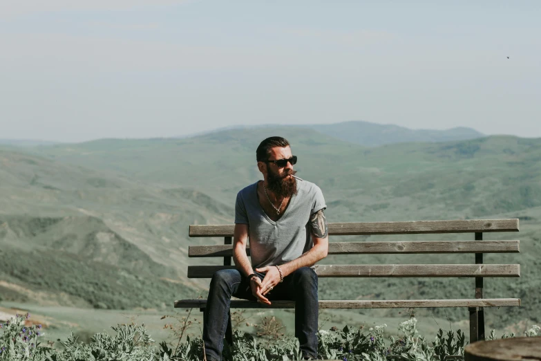 a man sitting on top of a wooden bench, by Matt Cavotta, pexels contest winner, rugged beard, on a hill, hipster dad, 3 5 years old