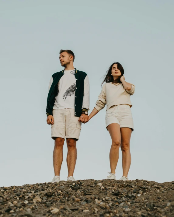 a man and a woman holding hands on top of a hill, trending on unsplash, renaissance, tan skin a tee shirt and shorts, non binary model, iceland, lizard king / queen forgiveing