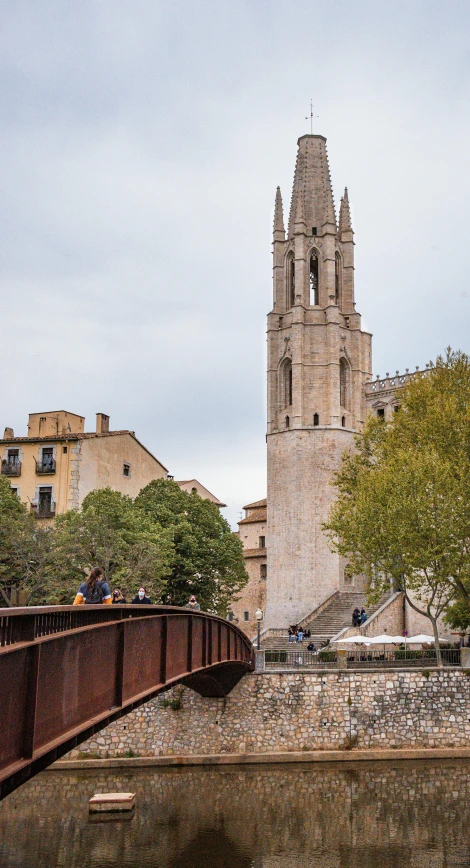 a bridge over a river with a clock tower in the background, inspired by Modest Urgell, romanesque, looking towards camera, square, exterior, golden towers