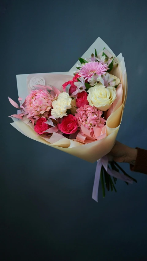 a person holding a bunch of flowers in their hand, white and pink, pink accents, on grey background, wrapped in flowers