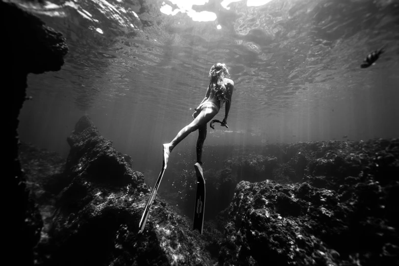 a person standing on a rock in the water, a black and white photo, by Caroline Mytinger, unsplash contest winner, mermaid cyborg with a laser whip, maui, scuba diving, nina agdal