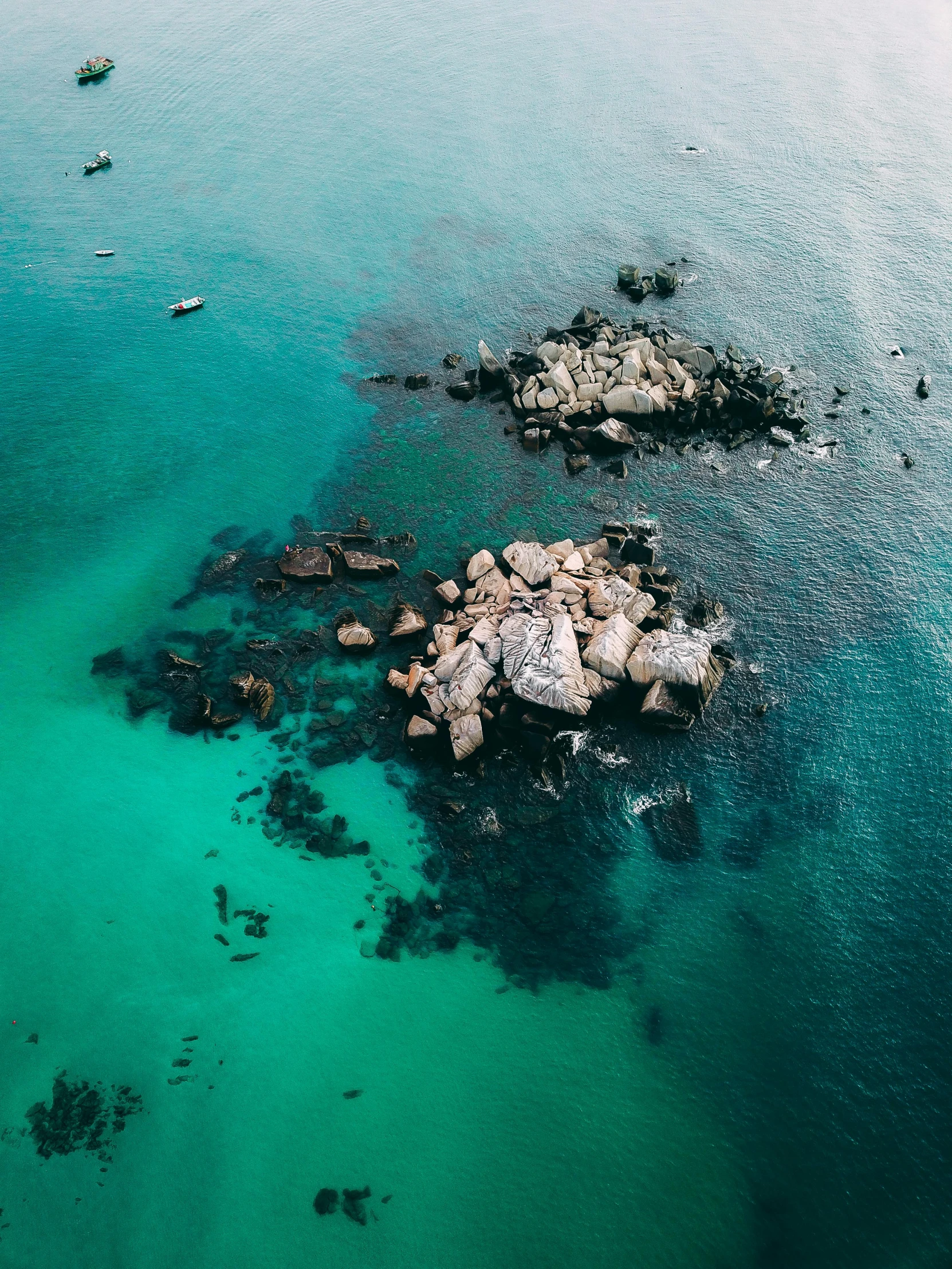 a group of boats floating on top of a body of water, by Ryan Pancoast, pexels contest winner, abel tasman, deep green, big rocks, birds eye photograph