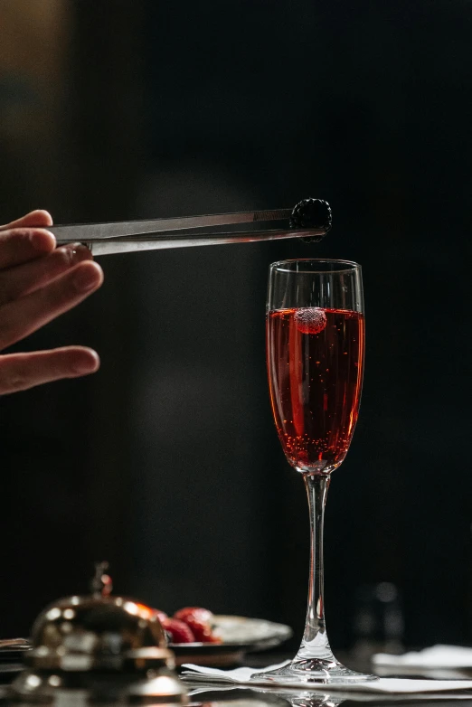 a person pouring a glass of wine into a wine glass, holding a syringe, with sparkling gems on top, crimson fork, very smoky paris bar