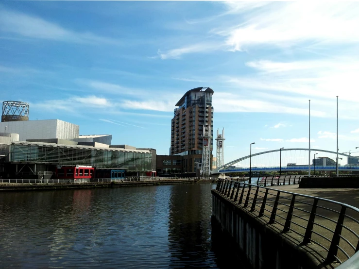 a bridge over a body of water next to tall buildings, a photo, inspired by Edwin Deakin, pexels contest winner, modernism, manchester, blue sky, thumbnail, docks