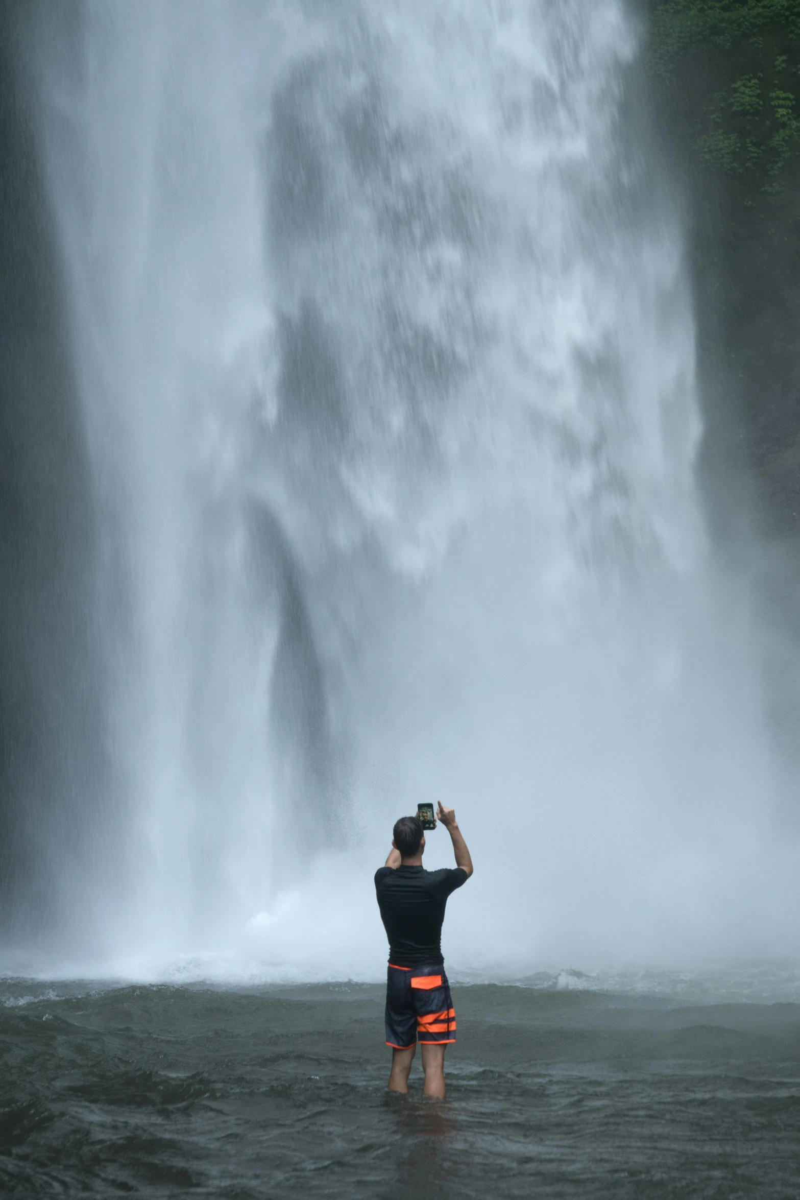 a man taking a picture of a waterfall, taken in the late 2010s, indonesia, 9/11, contemplating