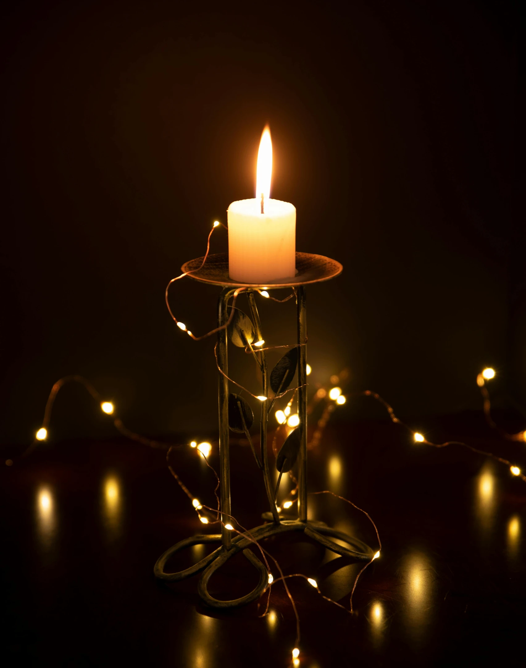 a lit candle sitting on top of a table, inspired by Ernest William Christmas, happening, ultra detailed wire decoration, medium close up, light scatter, standing in a dimly lit room