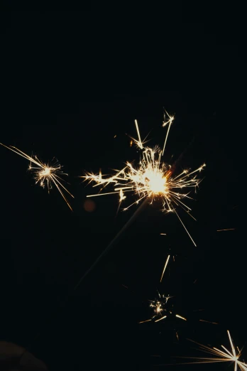a close up of a person holding a sparkler, pexels, light and space, black background with stars, grainy, low quality photo, shiny silver