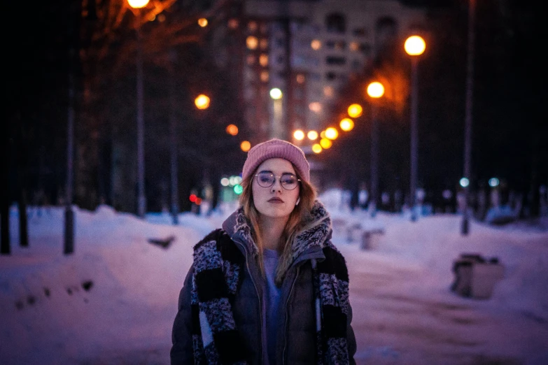 a woman standing in the middle of a snowy street, a portrait, inspired by Elsa Bleda, pexels contest winner, realism, hero pose colorful city lighting, wearing beanie, girl with glasses, neo norilsk