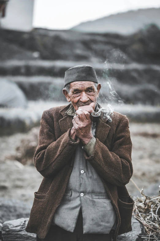 a man standing next to a pile of hay, inspired by Steve McCurry, pexels contest winner, sumatraism, smoking a cigarrette🚬, elderly, a handsome, nepal