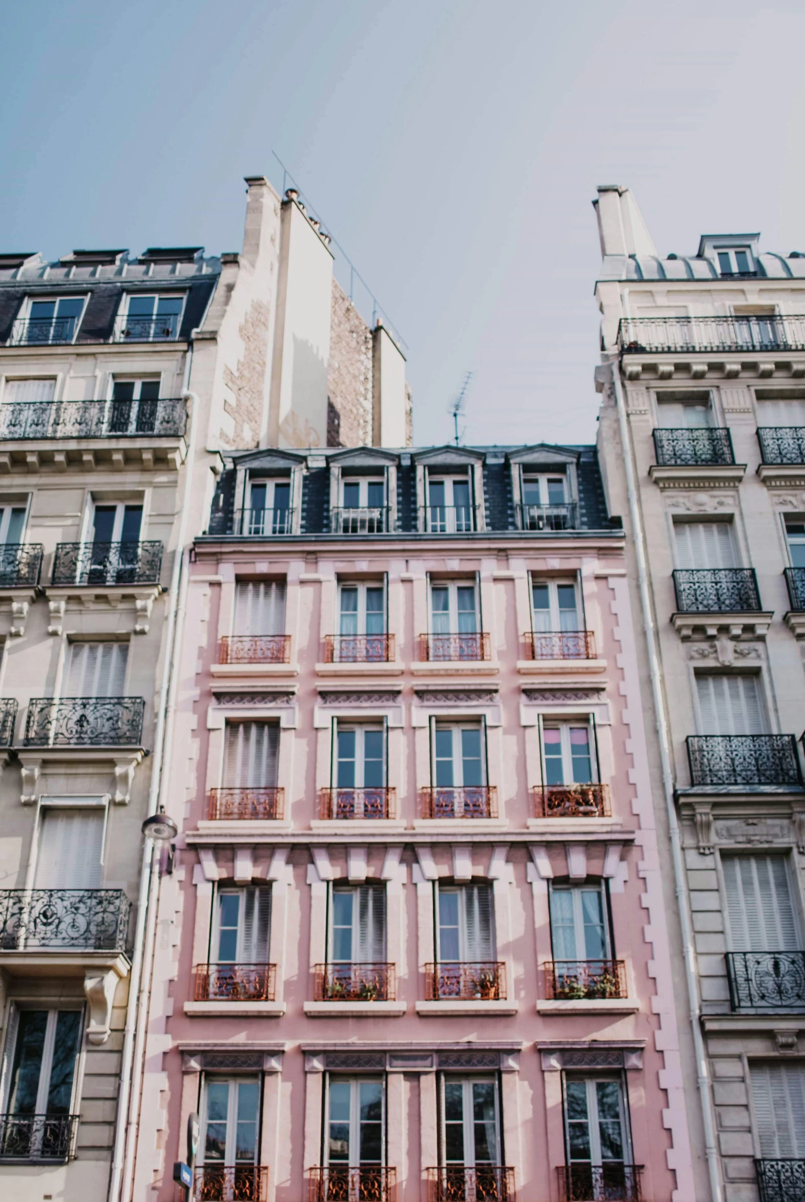 a couple of tall buildings next to each other, inspired by Wes Anderson, trending on unsplash, paris school, pink accents, quaint, pale colors, conde nast traveler photo