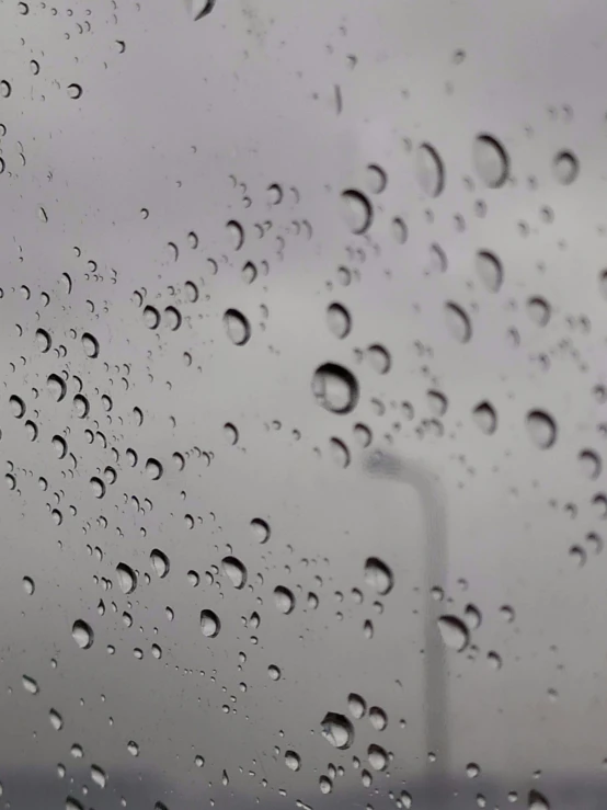 a close up of a window with raindrops on it, an album cover, pexels, grey, portholes, background image, inside of a car