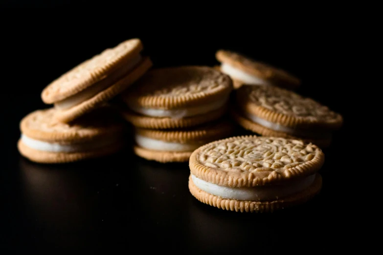 a pile of cookies sitting on top of a table, by Adam Chmielowski, unsplash, hyperrealism, on black background, cream, omega, backlighted